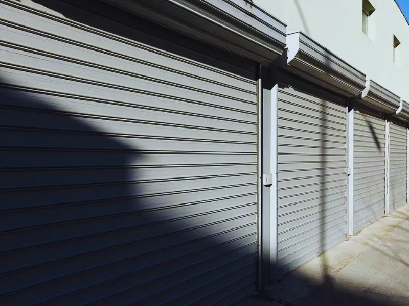 Row of heavy-duty industrial aluminum roller shutters installed on a commercial warehouse exterior in the Middle East.