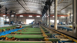 Freshly extruded long aluminum profiles resting on the cooling bed of a heavy-duty extrusion press line in the manufacturing plant.